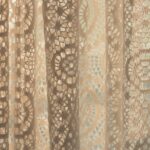 Tenda bianca e leggera appesa a una finestra, con luce che filtra attraverso il tessuto.