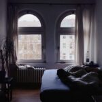 Immagine di una camera fresca e ben ventilata con tende aperte e ventilatore acceso.