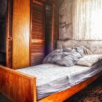 Muffa visibile dietro un letto, evidenziando l'umidità e il problema di scarsa ventilazione.