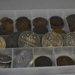 Monete rare e antiche con strumenti per la pulizia su un tavolo di legno.