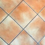 Immagine di una persona che pulisce le fughe con una soluzione naturale, senza utilizzo di candeggina.